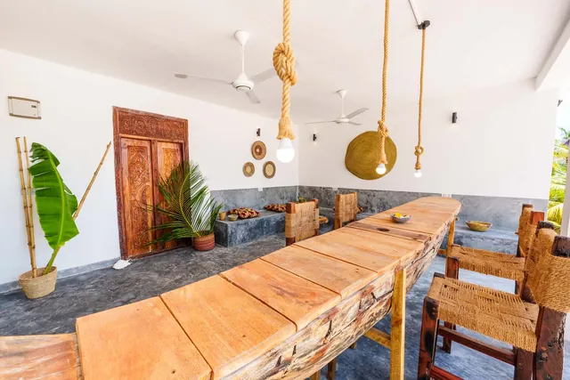 Long wooden table with chairs under pendant lights in the Open Living Space