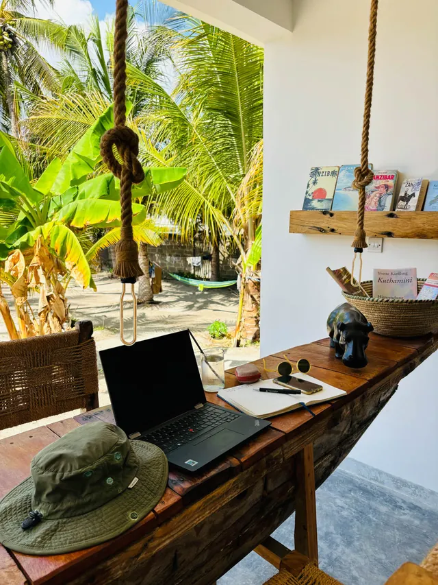 Workspace with laptop on a wooden table, looking out into the palm garden